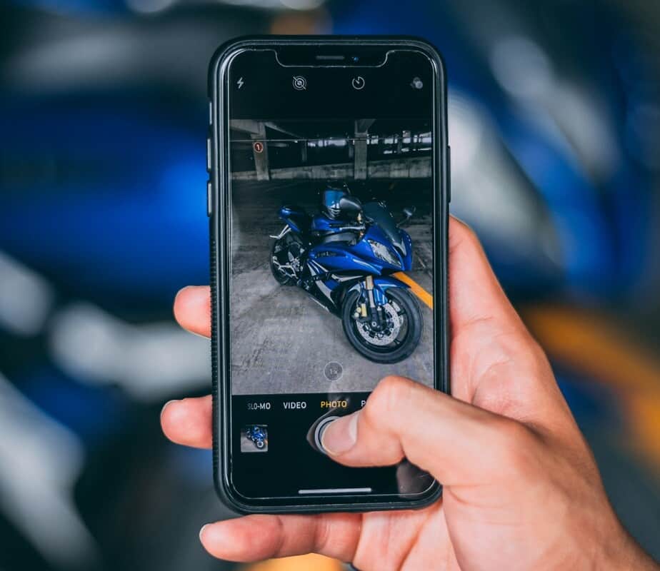 Hand holding a mobile phone with motorcycle displayed